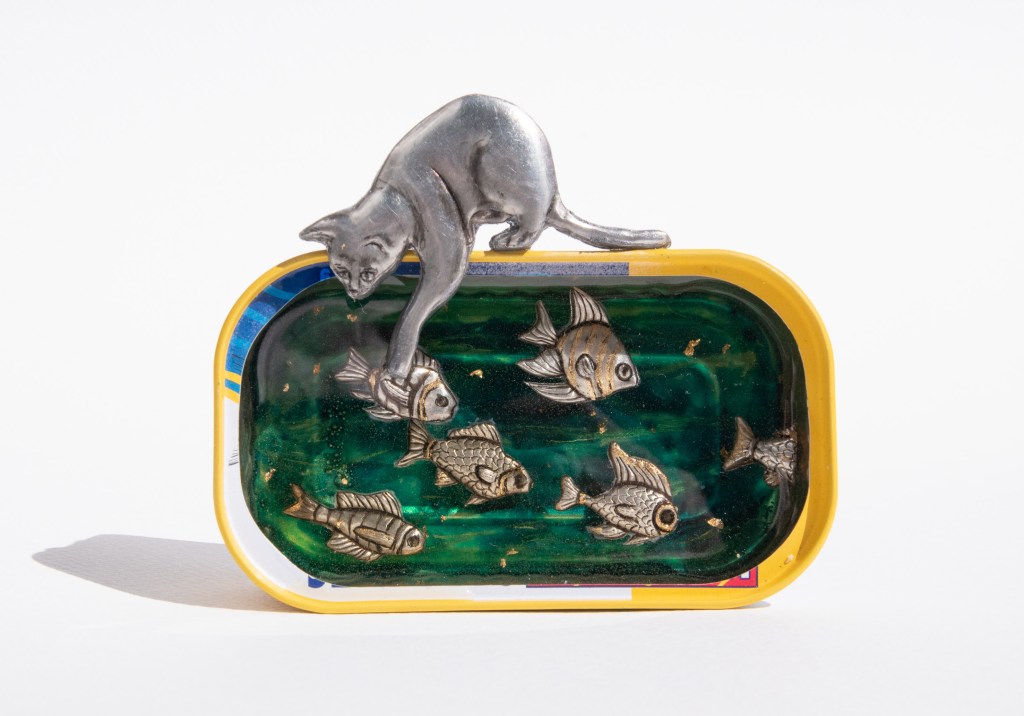 Pewter art by Sandy Griffiths entitled Lucky cat. Embossed Pewter cat looking at fish set in resin in a Lucky Fish Sardine tin. 80 x 105mm