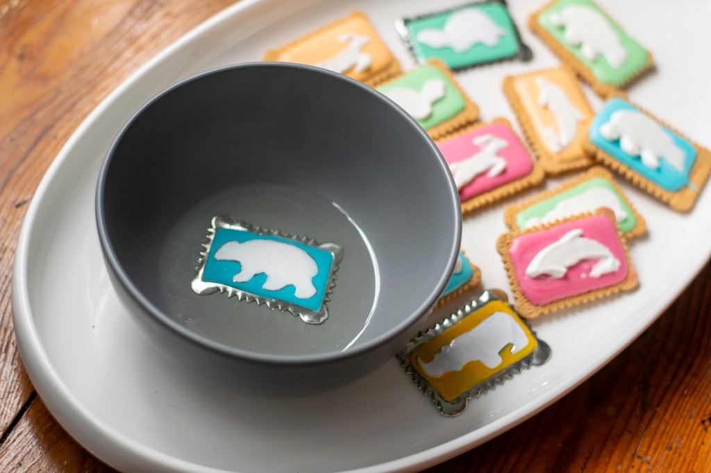 Zoo Biscuit Bowl. Grey ceramic bowl with embossed pewter set in resin. 170mm. With Zoo Biscuits on a platter for comparison to the pewter look alike.