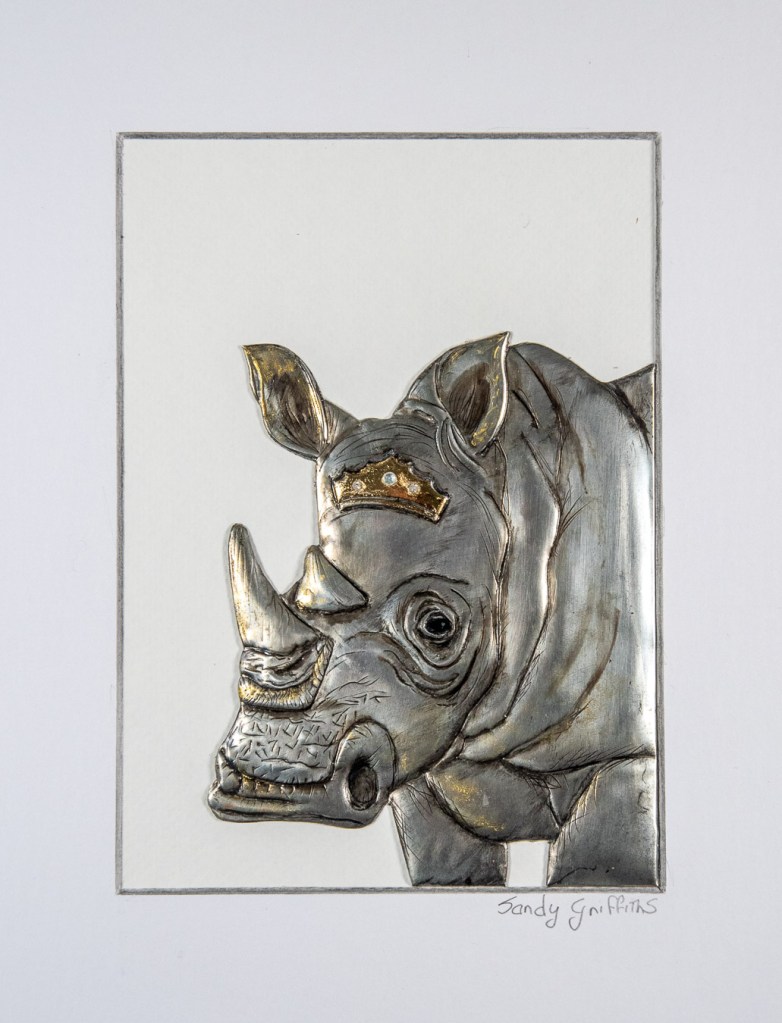Hand-embossed pewter Rhinoceros with gold leaf and paint in a white box frame, by Sandy Griffiths.