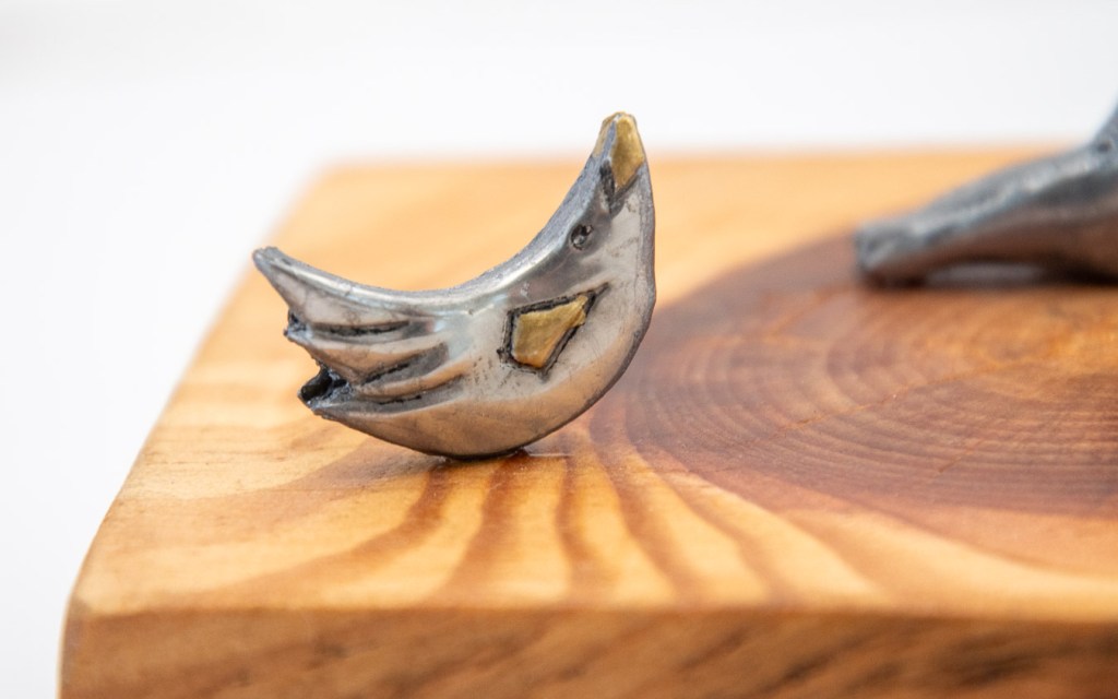 Hand-embossed pewter girl holding a balloon and a bird set on clay, mounted on a piece of knotty Pine, by Sandy Griffiths. 140 x 100 x 230mm.