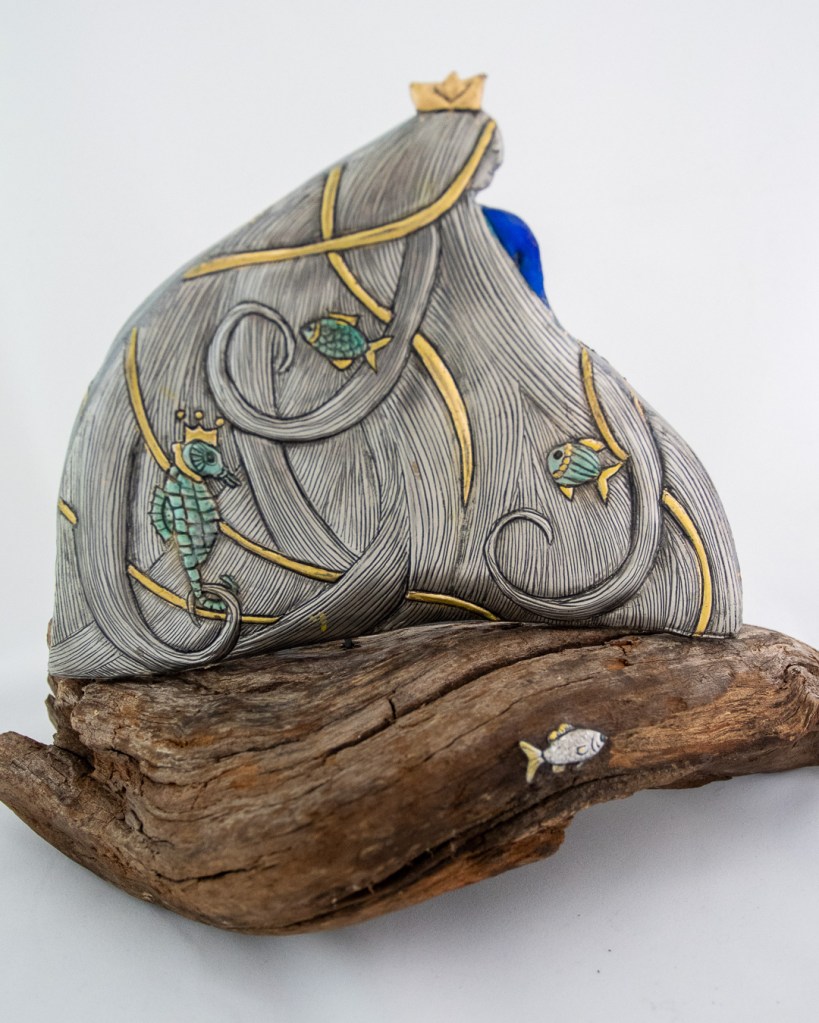 She carries the ocean in her hair. Hand-embossed pewter and clay set on driftwood. Size 320mm x 190mm x 230mm high.